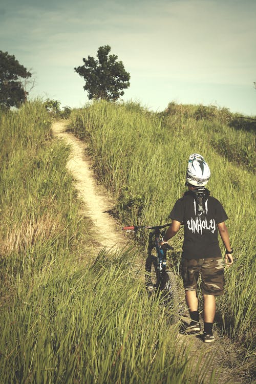 Man in Black Shirt and Brown Shorts Holding Bicycle