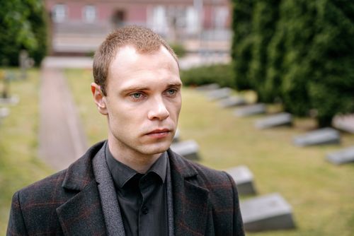 Free A thoughtful man in a cemetery, deep in contemplation, wearing a dark coat. Stock Photo