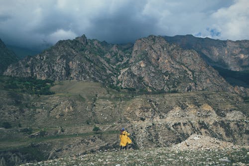 Person in Yellow Jacket Hiking in Mountains