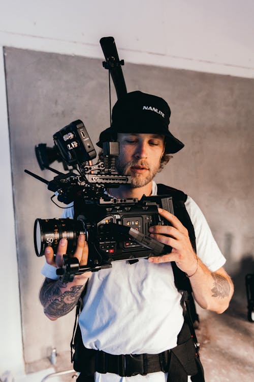 A Man in a White Shirt and a Bucket Hat Using His Camera
