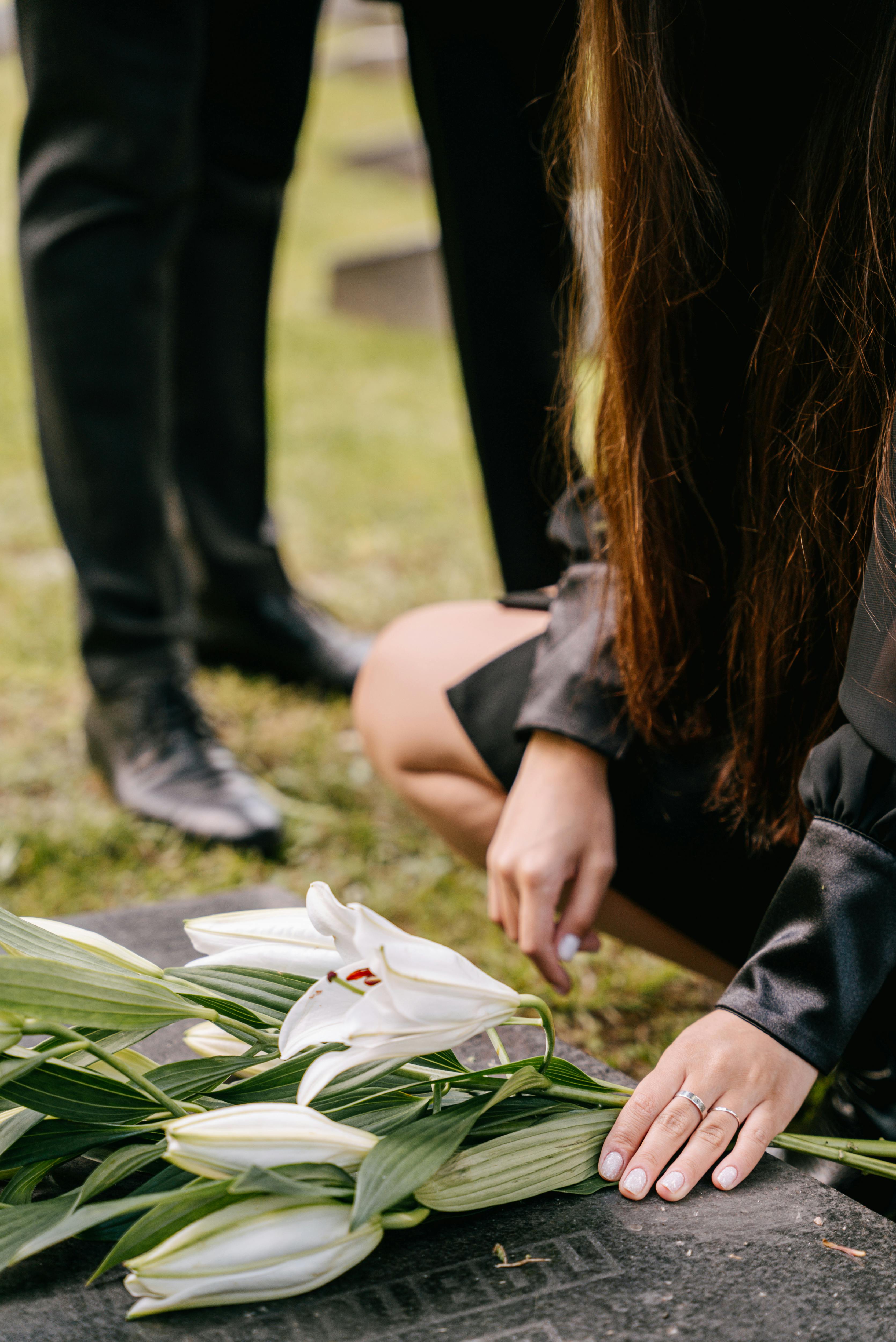 a close up shot of a person putting flowers on a headstone