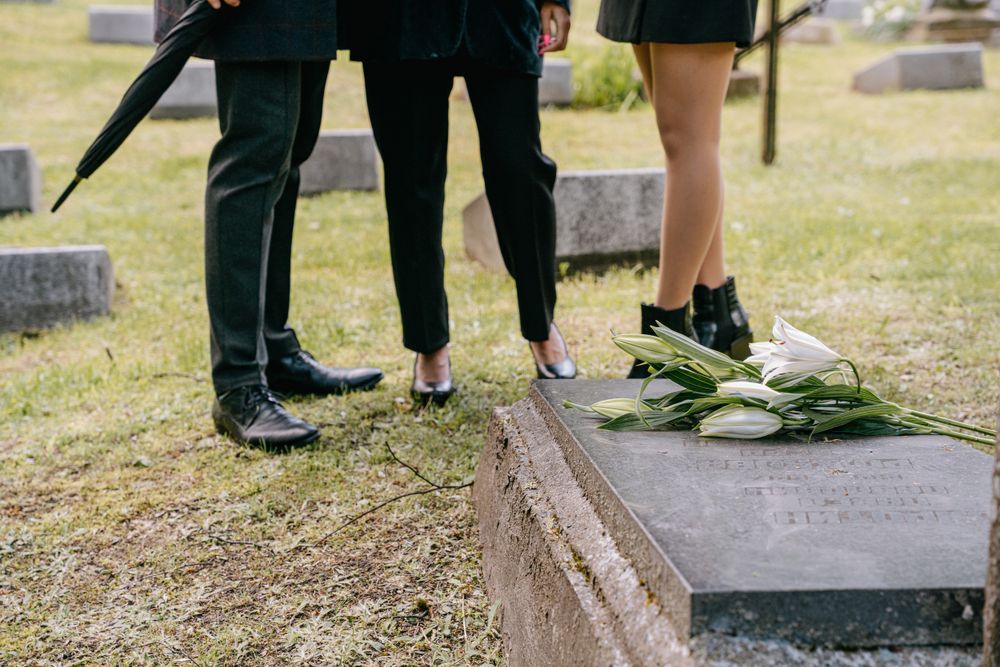 Mourners gathered near a grave with white flowers
