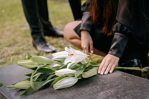 Woman in Black Clothes Holding White Flowers on Grave