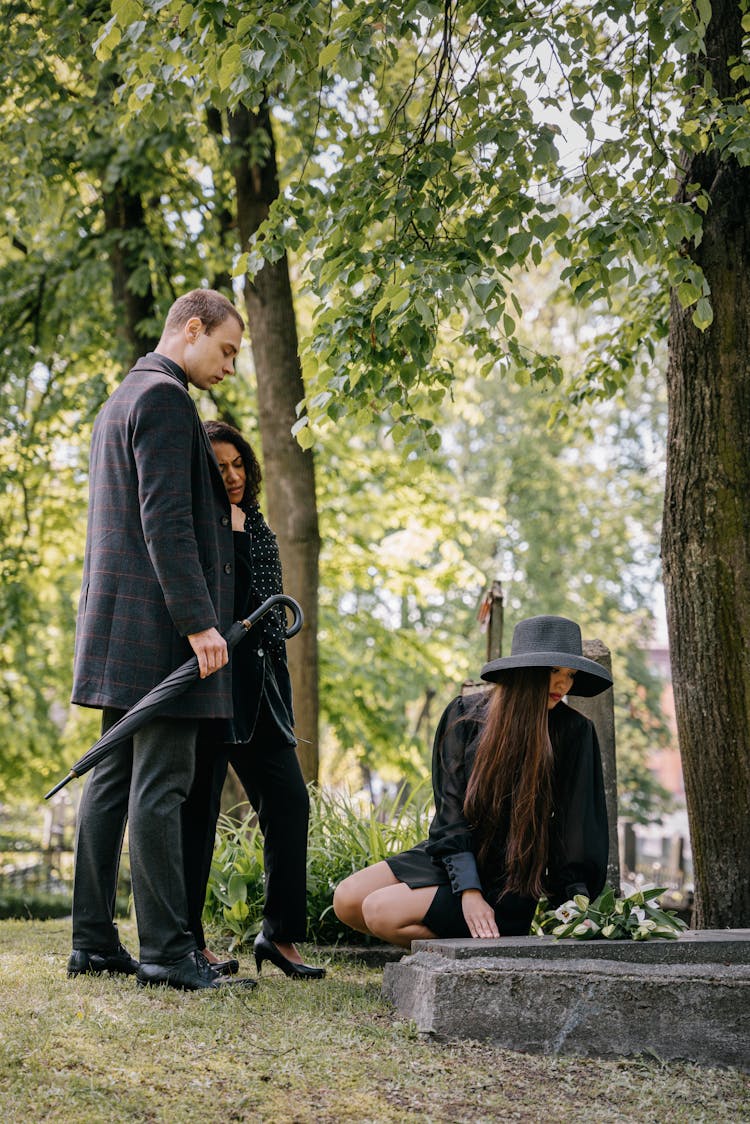 People In Black Outfits Grieving At A Cemetery