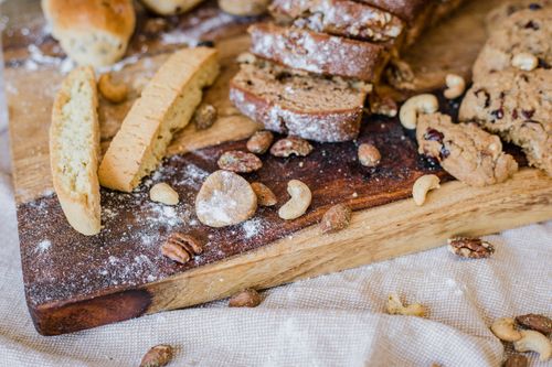 Free Delightful spread of sliced bread, cookies, and mixed nuts on a wooden board. Stock Photo