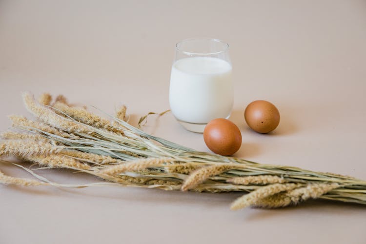 Close-Up Photo Of Two Brown Eggs Beside A Glass Of Milk And Wheat