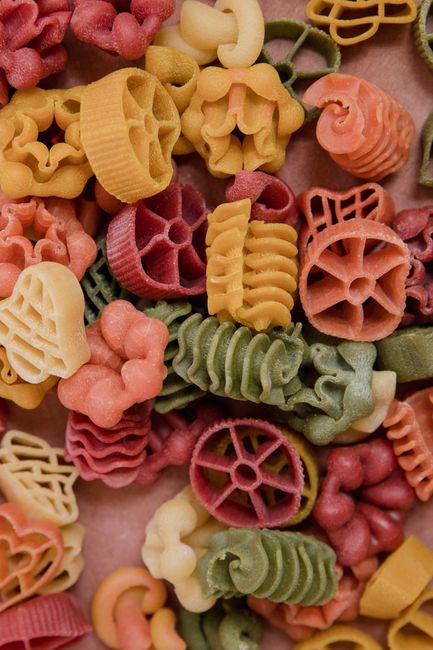 Overhead shot of several bowls filled with different dried pasta shapes including penne, fusilli, orecchiette, and spaghetti.