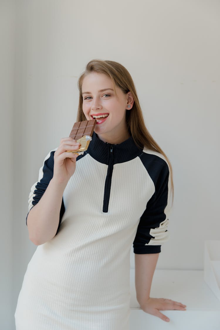 Beautiful Woman In White Dress Eating Chocolate