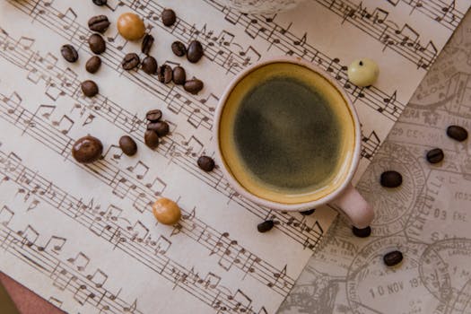Cup of coffee surrounded by coffee beans on musical sheet papers, creating a harmonious still life.