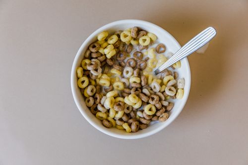 Free Top view of a ceramic bowl filled with cereal loops and milk, featuring a spoon. Stock Photo