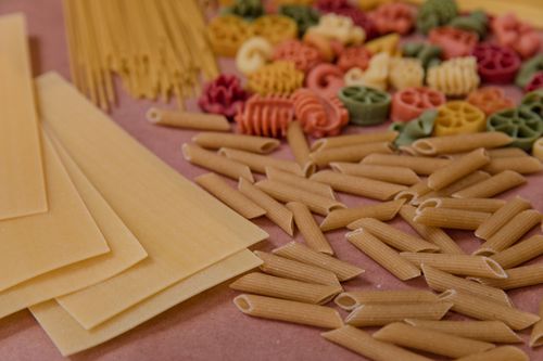 Free Assorted uncooked pasta varieties displayed on a wooden surface, perfect for culinary concepts. Stock Photo