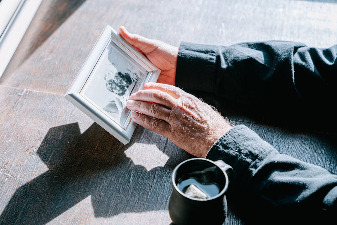 Free A Person in Black Long Sleeves Holding a Picture Frame Stock Photo