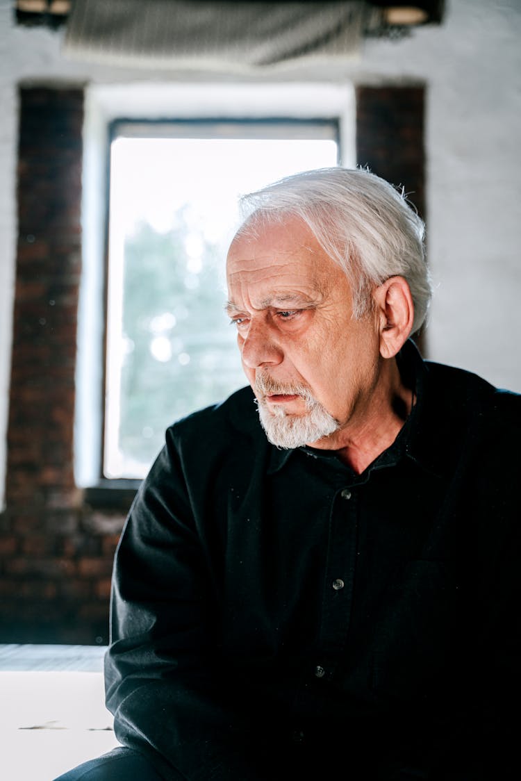 An Elderly Man In Black Long Sleeves With A Sad Face