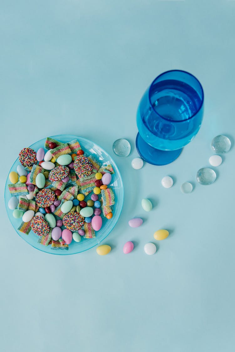 A Plate Of Assorted Candies Beside A Glass Of Water