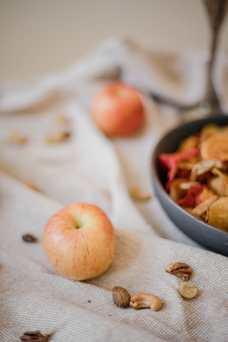 Red Apple Fruit And Pieces Of Mixed Nuts On A Textile