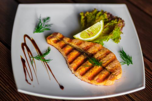 Free A delectable grilled salmon fillet served with lime wedge and fresh dill on a ceramic plate. Stock Photo