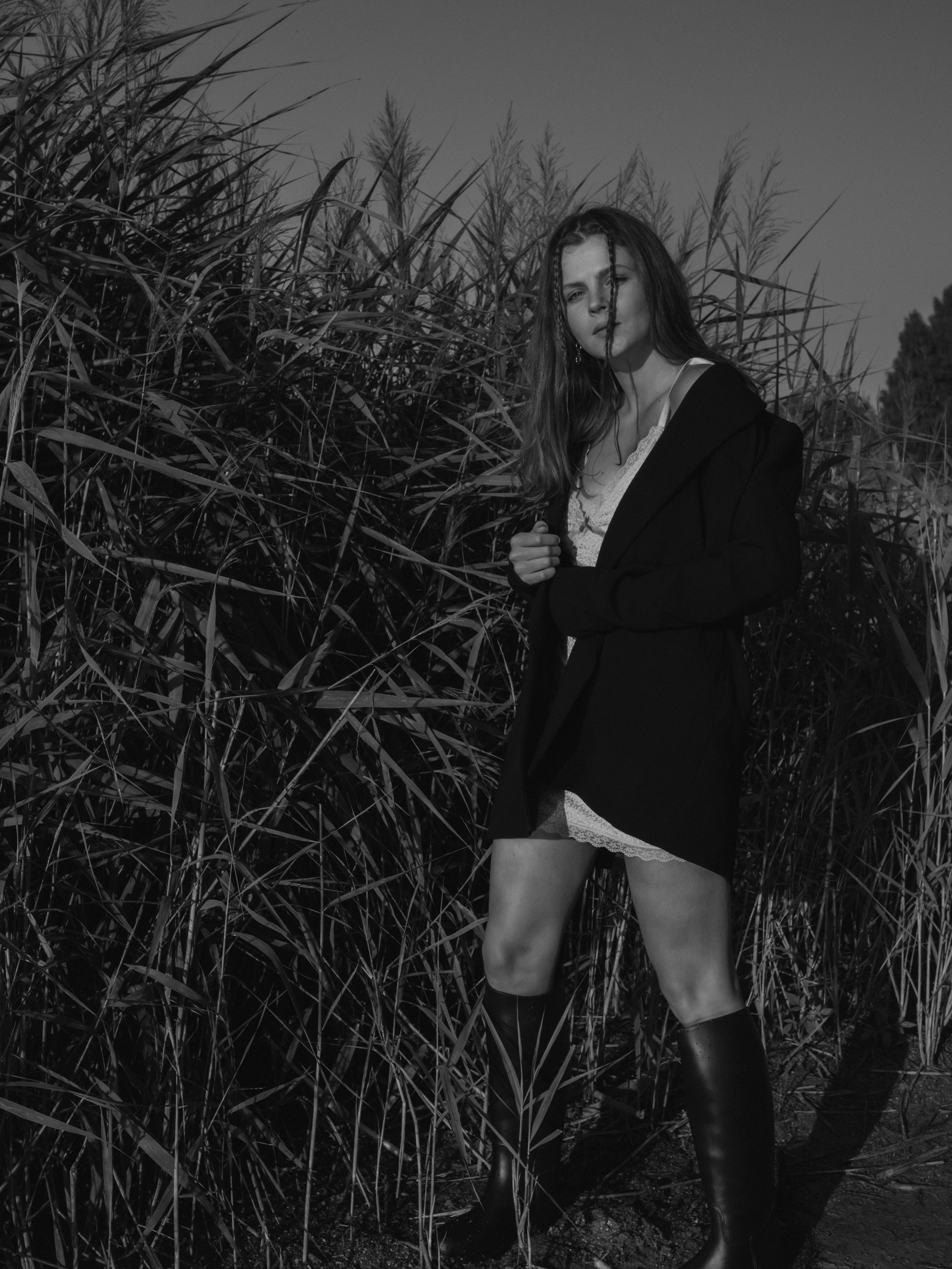 Back View Shot Of A Woman In Black Bodysuit Standing On Grass Field While Stretching Arns · Free