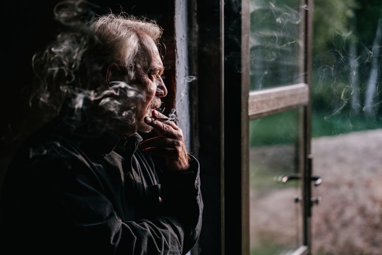 Elderly Man In Black Shirt Smoking Beside Open Door