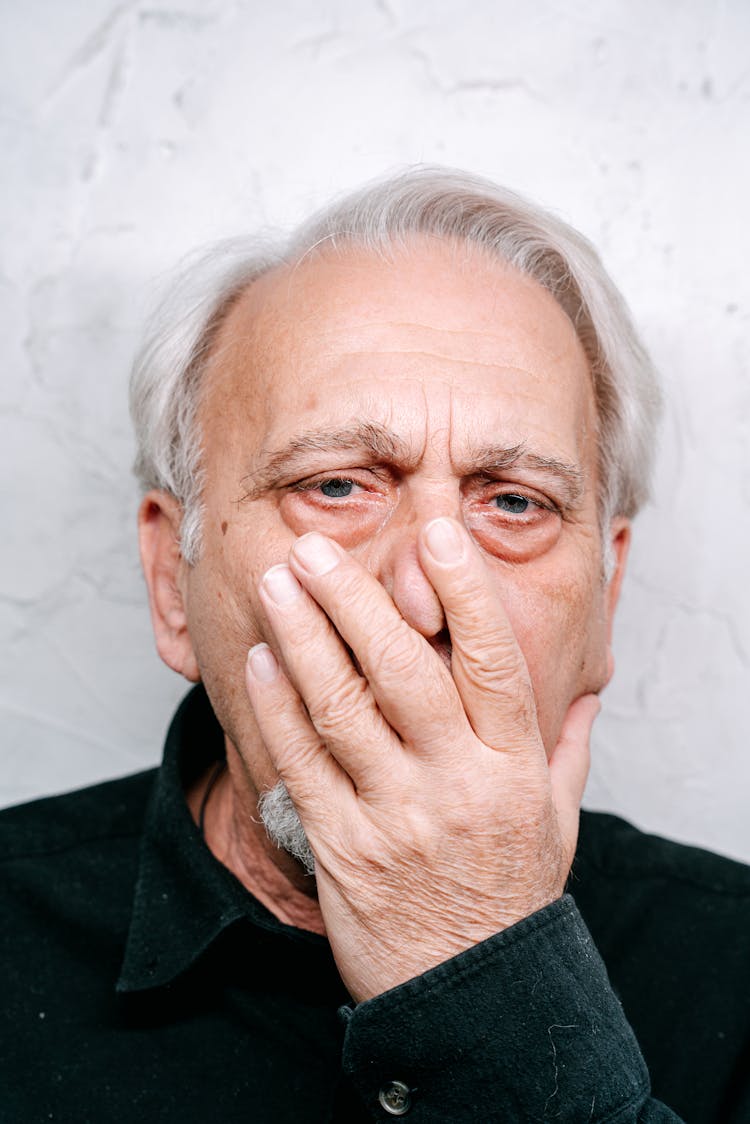 Elderly Man In Black Shirt Covering His Face