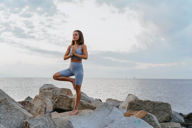 A Woman Doing A Yoga Exercise Near The Ocean During Morning