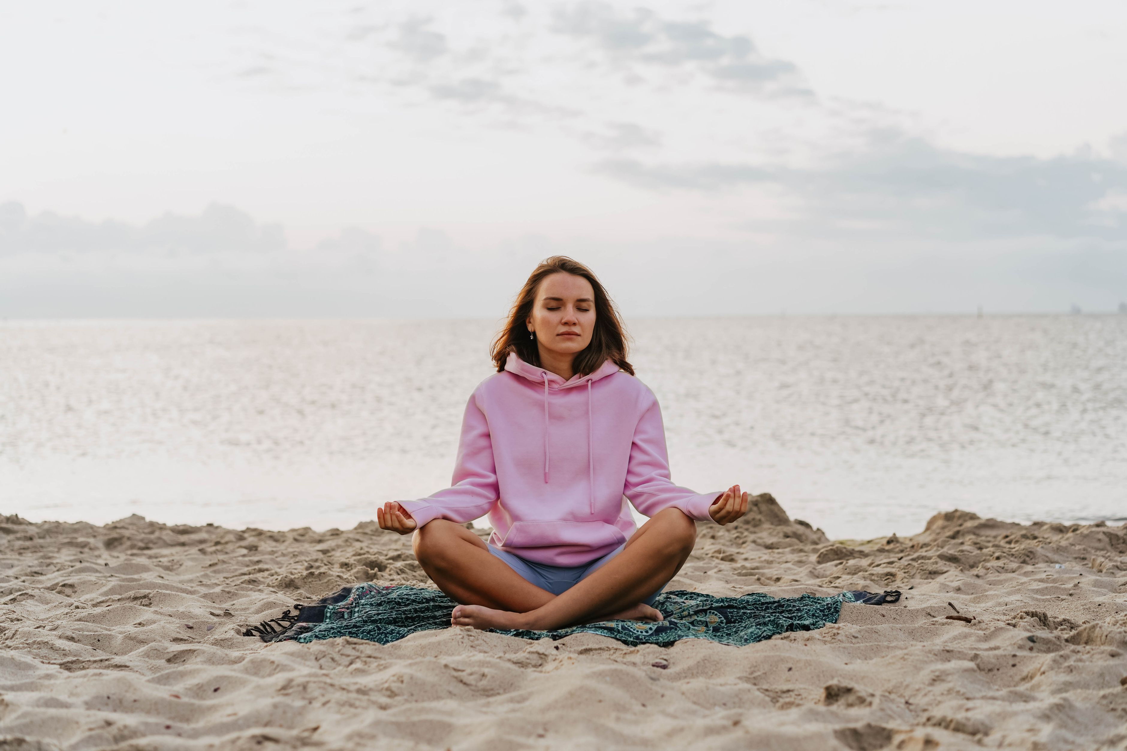 Woman meditating peacefully on a beach at sunrise