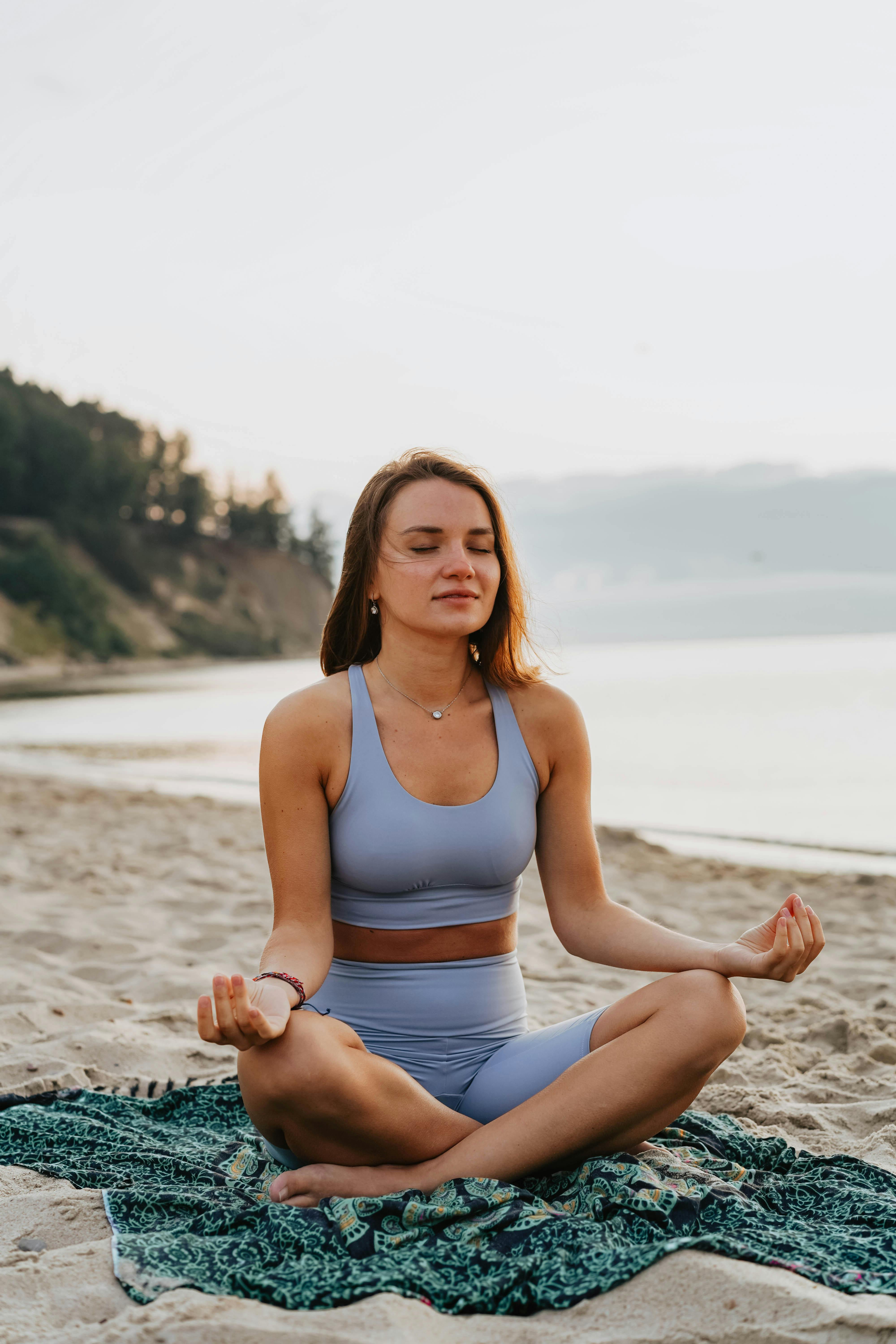 a woman doing a meditation on a beach during morning