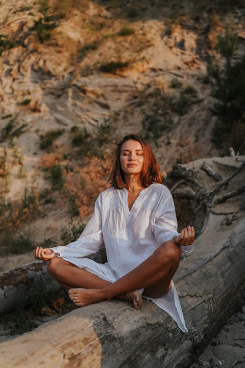 A Woman Doing a Meditation on a Tree Log during Morning