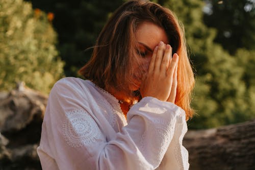 Free Woman in White Long Sleeves Praying Outside Stock Photo