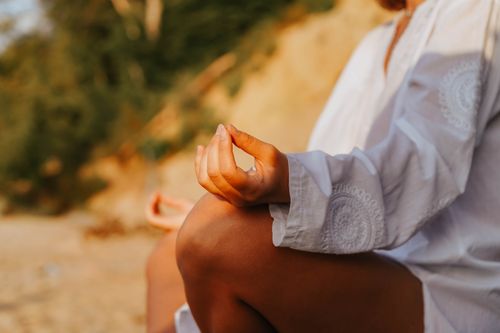 Free A close-up of a person meditating outdoors, capturing mindfulness at sunset on a beach. Stock Photo