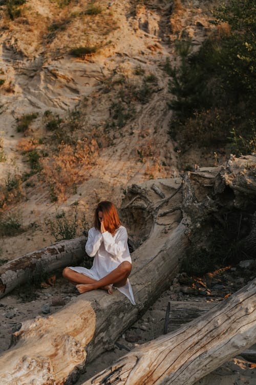 
A Woman Meditating on a Tree Trunk
