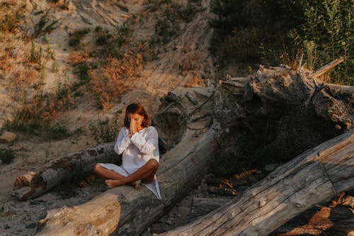 
A Woman Meditating on a Tree Trunk