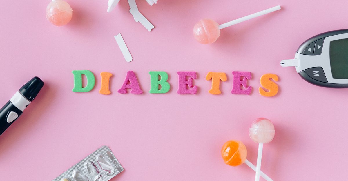 Flat lay image depicting diabetes with glucometer, pills, and lollipops on a pink background.