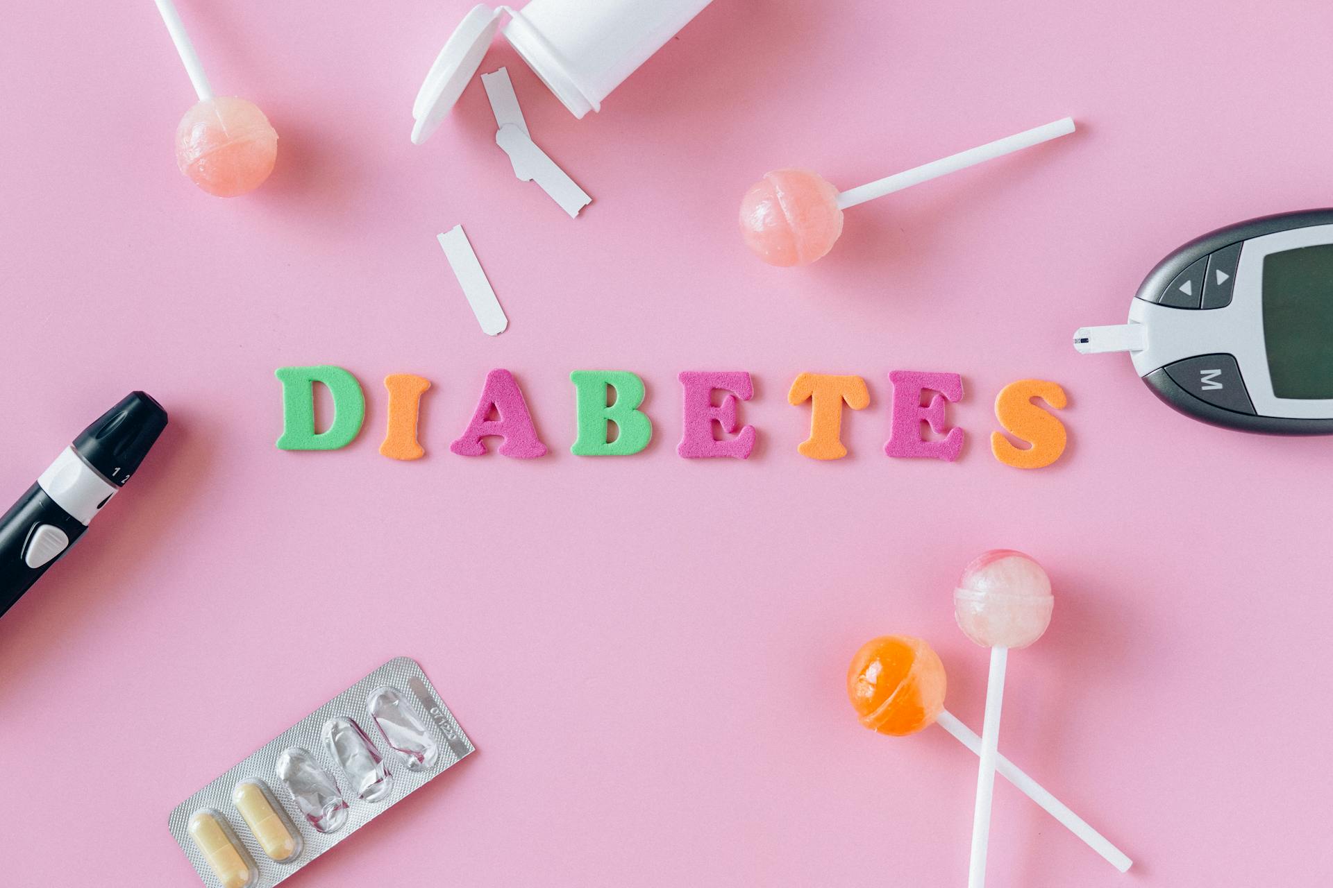 Word "Diabetes" Made of Colorful Letters Lying among Lollipops, Medication and Blood Sugar Monitor Devices