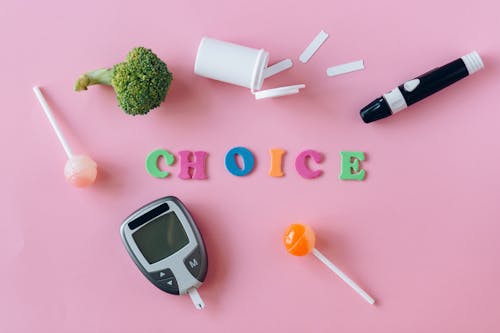 Word "Choice" Made of Colorful Letters Lying among Diabetes Equipment, Sweets and Broccoli