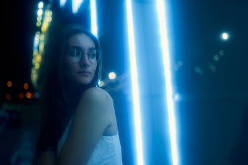 Woman in White Tank Top Standing Beside the Neon Lights