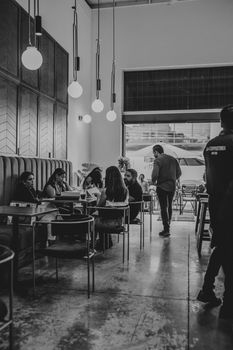 Monochrome image capturing people socializing in a modern café setting.