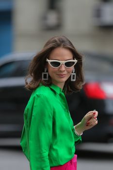 Fashionable woman with bold earrings and sunglasses on New York City street.