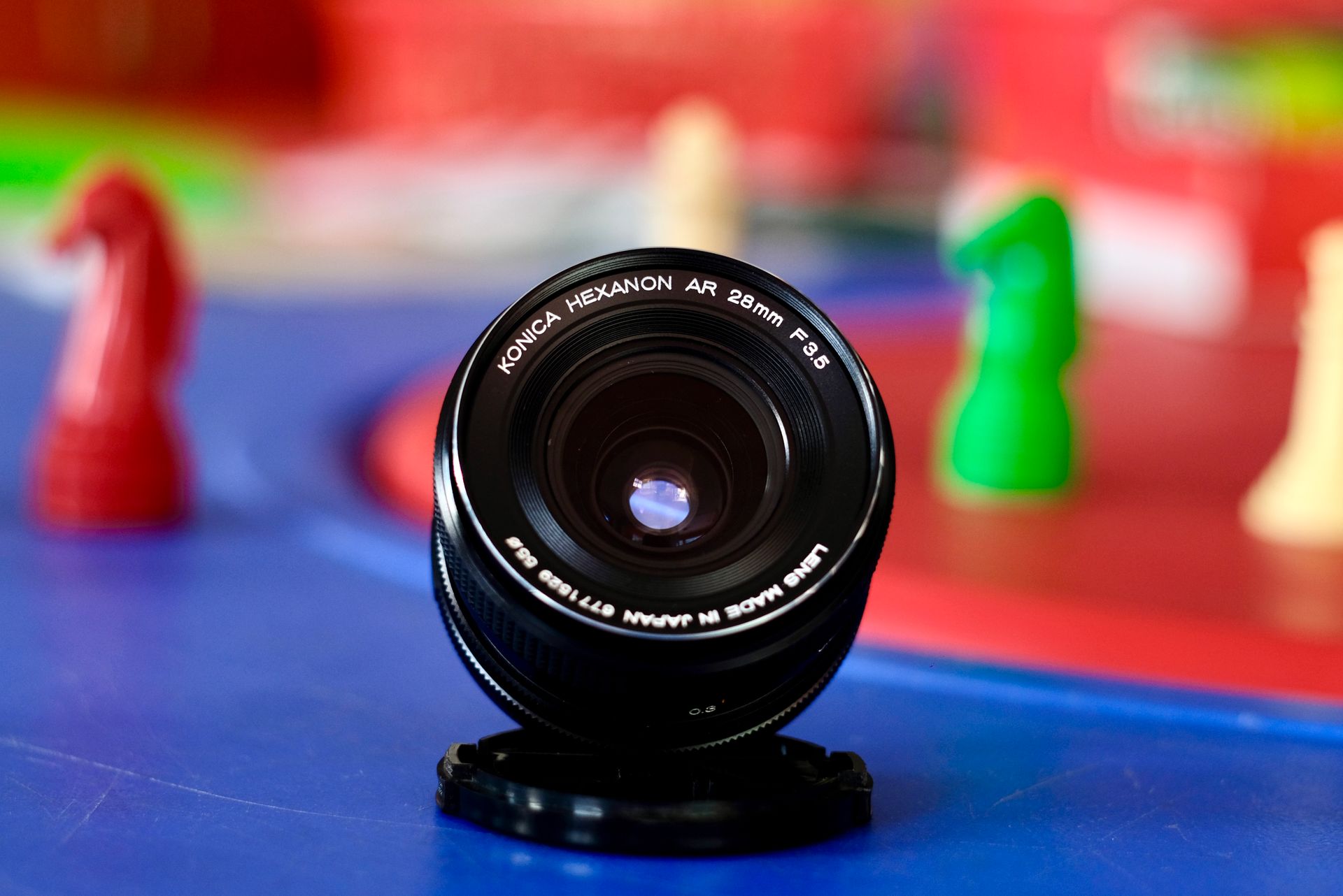 Close-up view of a Konica Hexanon AR 28mm lens with colorful blurred background