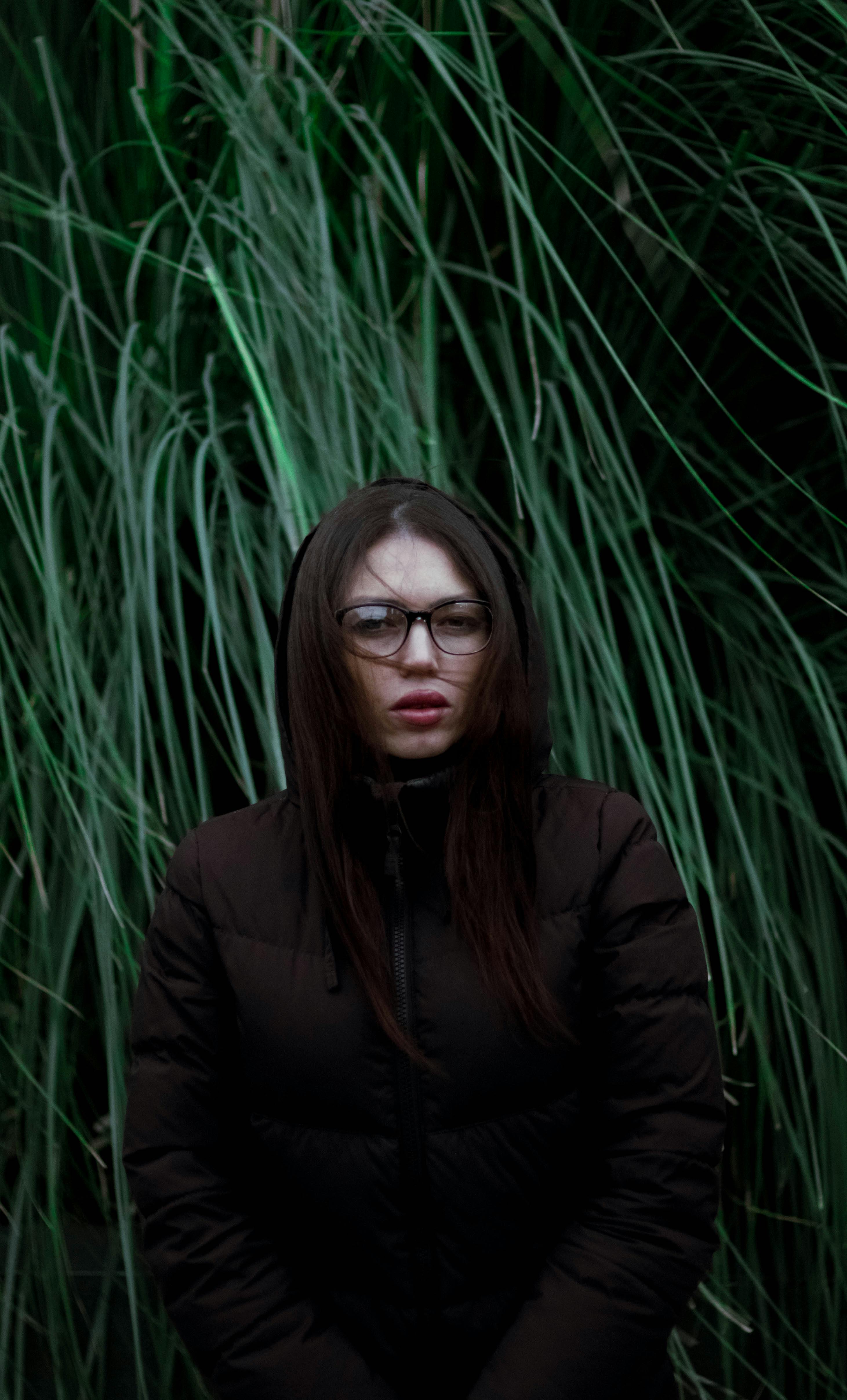 young woman in warm coat standing among long grass