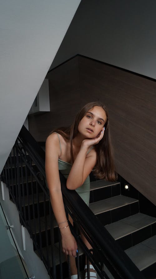 A Woman Standing on the Stairs with Her Hand on Her Chin