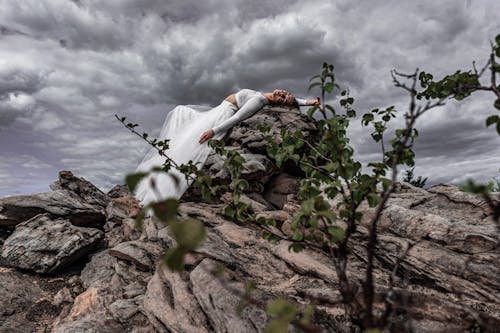 Woman in White Dress Lying on a Big Rock