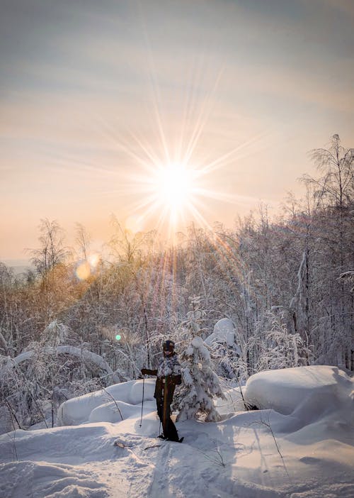 A Person in Black and White Jacket Standing on Snow Covered Ground