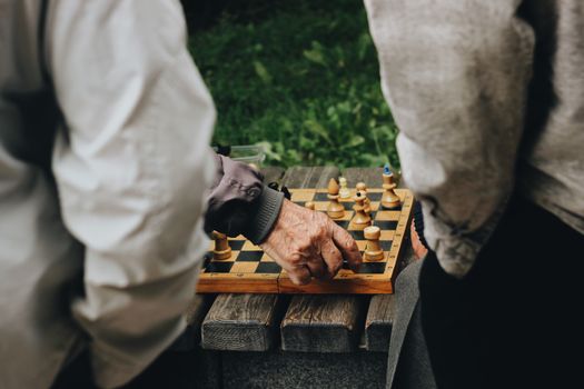 Close-up of senior adults playing chess in a park, capturing leisure and strategy.