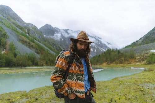 Man Wearing a Hat Standing on Riverside