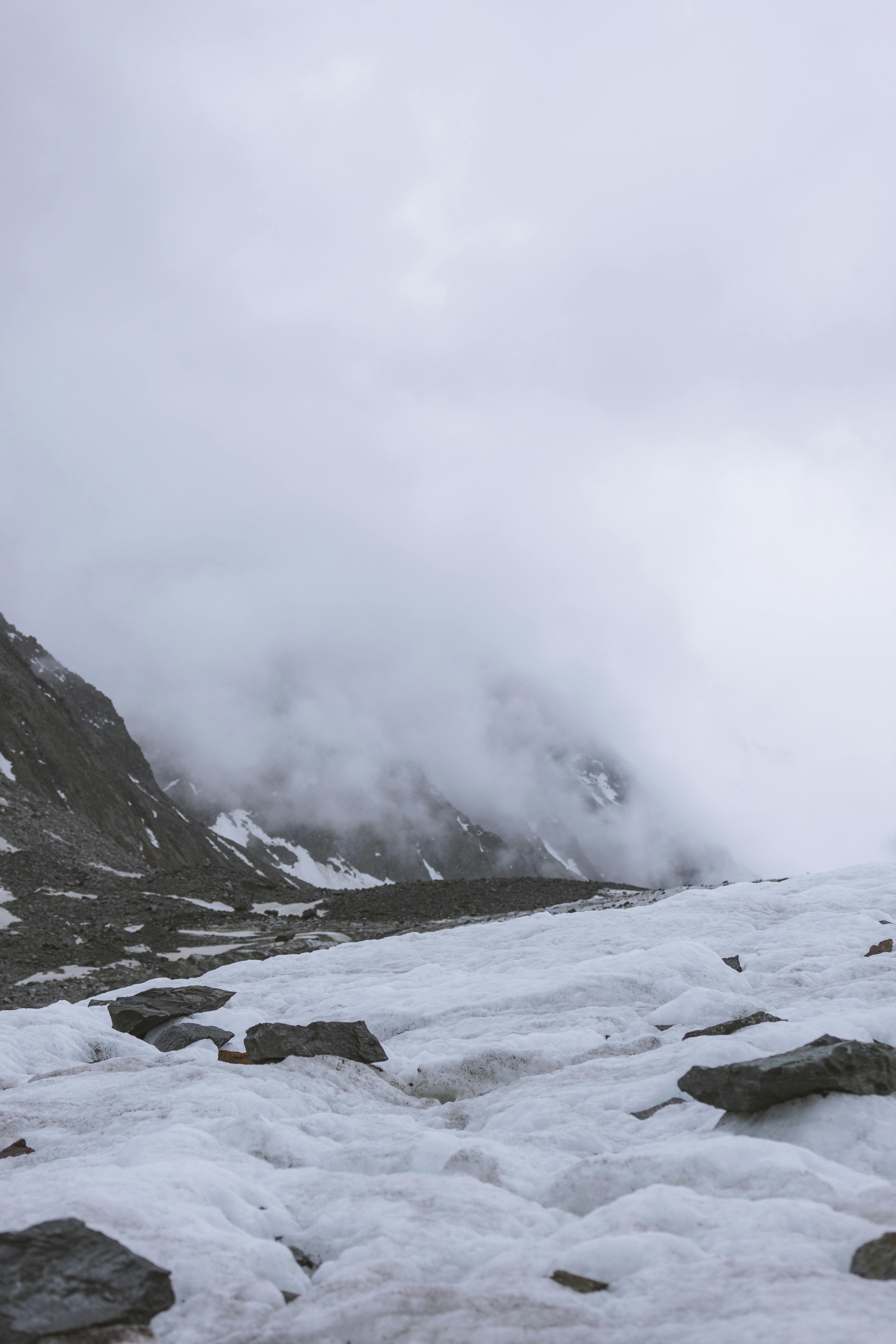 Prescription Goggle Inserts - Fog envelops a snow-covered mountain, creating a dramatic winter scene with rocky formations.