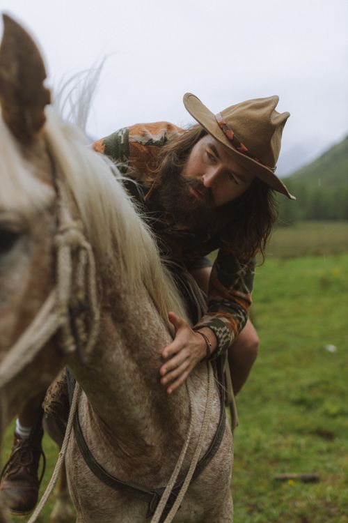 Free A cowboy riding a horse in a lush green landscape, showcasing a rustic lifestyle. Stock Photo