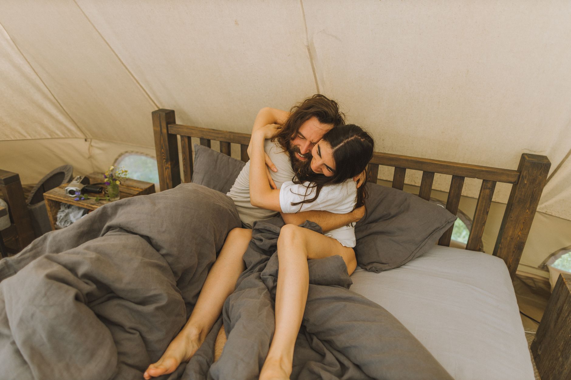 Happy couple embracing in a cozy tent, conveying love and togetherness.