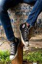 Person in Blue Denim Jeans Wearing Black and White Converse All Star High Top Sneakers