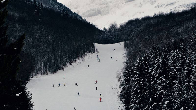 Snow-covered ski slope running between dark forested hills