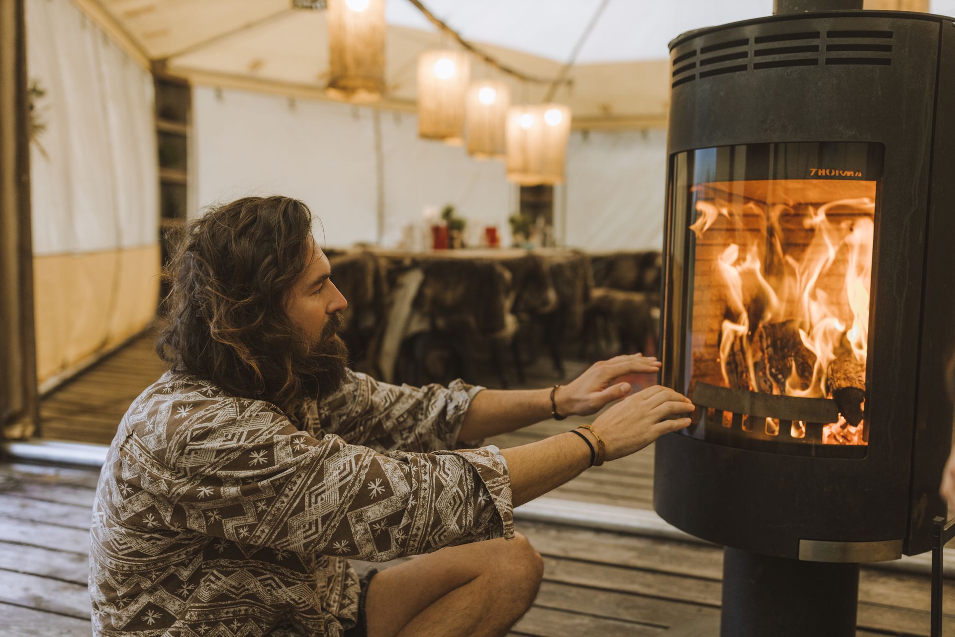 A Man Warming up his Hands by a Fireplace